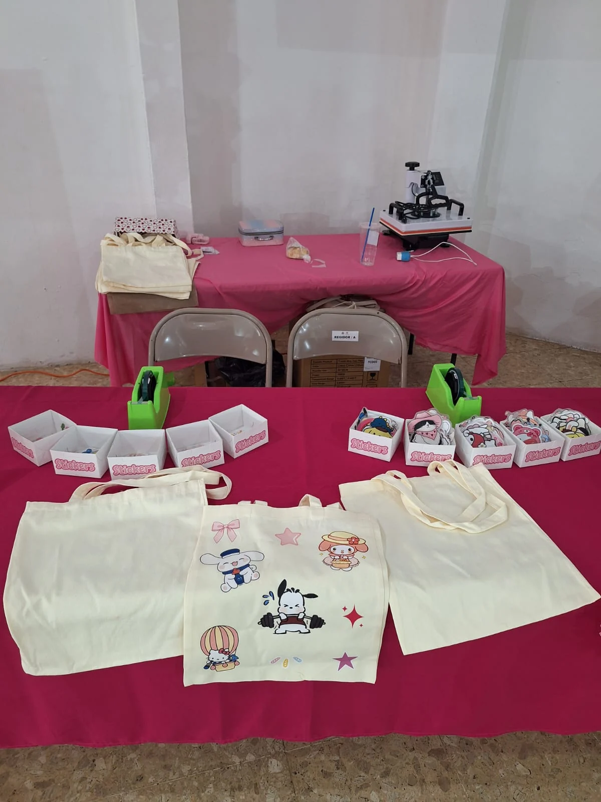 Mesa con playeras, bolsas y stickers disponibles para personalizar